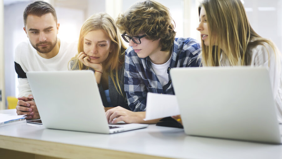 Group of talented young male and female journalists watching training webinar about live broadcasting reportage during lesson in university using laptop computers and free wireless internet access